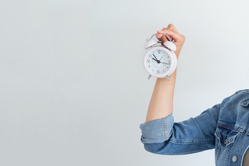 Asian woman holding a pink alarm clock on a white background. the concept of time management. get...