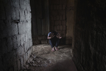 Helpless little girl sitting on floor against old earth brick wall,stop violence and abused children,human trafficking concept