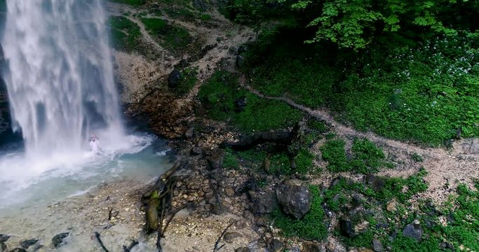 European man with beard is doing waterfall-meditation while standing under big waterfall in austria, wildensteiner waterfall
