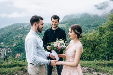 Walking newlyweds in nature. Groom and bride against the background of mountains and the sea. The priest blesses the young.