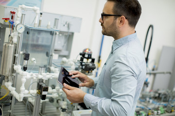 Handsome young man in the electronic workshop holding digital tablet