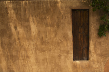 Fototapeta premium Wooden Gate in an Adobe Fence with a Security Window, Santa Fe, New Mexico