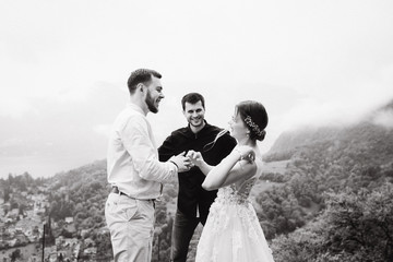 Walking newlyweds in nature. Groom and bride against the background of mountains and the sea. The priest blesses the young.