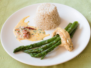 Chicken breast stuffed with asparagus in creamy sun-dried tomato sauce served with rice