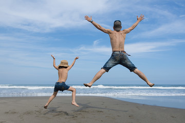 ビーチでジャンプする父と子供