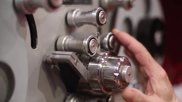 Human hand checking old professional analog multitrack studio tape player reel sprocket and head