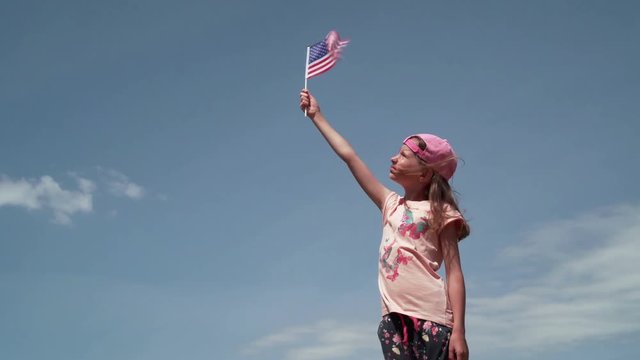 Girl waving US flag on the sky background 4K
