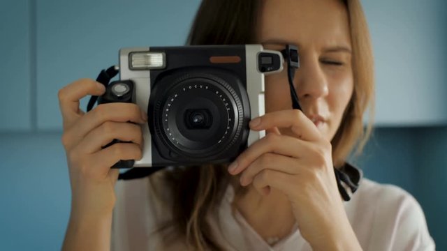 In this footage you can see beautiful young female photographer using instant photo camera to make film picture. It is very stylish, hipster type of photography.