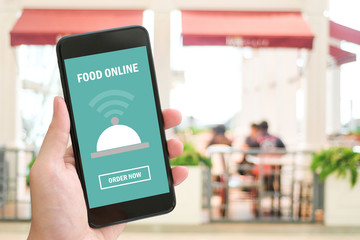 Hand holding smart phone with food online device on screen over blur cafe background, with copy space for text, mock up, template, food online, food delivery concept