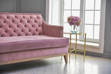 Beautiful colorful bouquet of hydrangeas is in a vase on a table with pink sofa