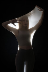 Girl posing in sportswear on a black background in a transparent bag