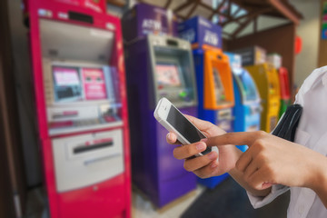 Girl use mobile phone, blur image at ATM machine as background.