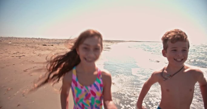 Young boy and girl having fun running on the beach
