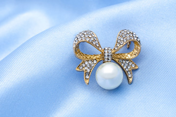 gold brooch bow with pearl and diamonds isolated on silk