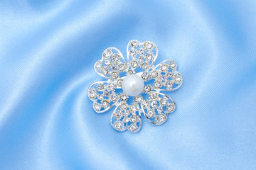silver brooch flower with pearls and diamonds isolated on silk