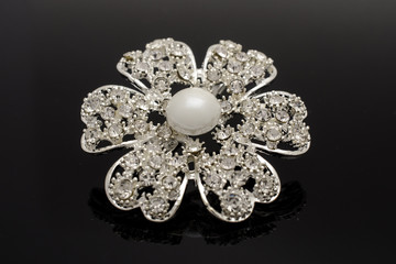 silver brooch flower with pearls and diamonds isolated on black