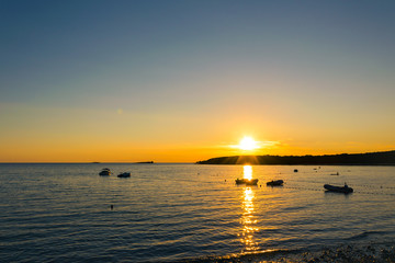 Coucher de soleil sur la plage avec des bateaux au loin
