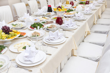 served festive dining table with dishes on plates, chairs, vegetables, fruits, greens, food