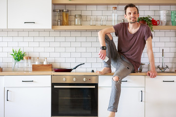 Photo of man sitting in kitchen with phone in hands