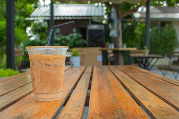 Naklejka premium Iced coffee on a wooden table in the garden.