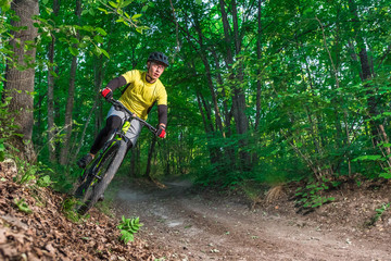 Fototapeta na wymiar A mountain biker rides the slope in the forest.