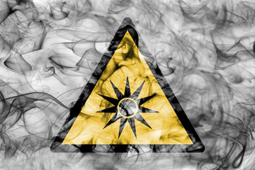 Optical radiation hazard warning smoke sign. Triangular warning hazard sign, smoke background.