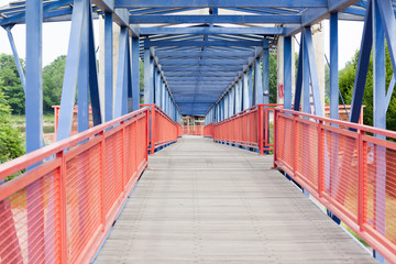 Pedestrian bridge made of wood and steel in red and blue