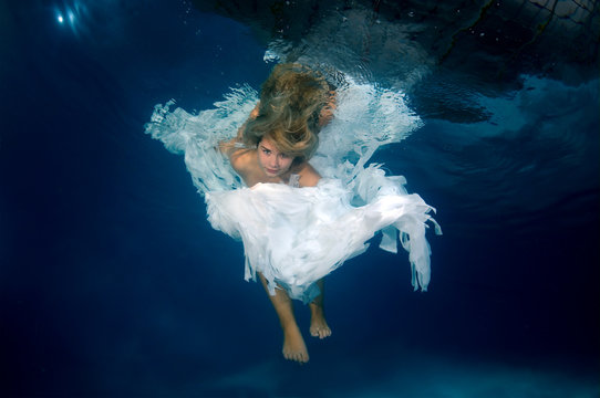 Young beautiful woman in the image of an angel underwater