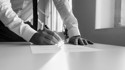 Greycale image of a man signing contract or document