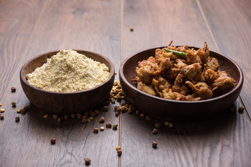 Chick pea flour or Besan powder in a ceramic or wooden bowl along with fried onion pakora or kanda bajji