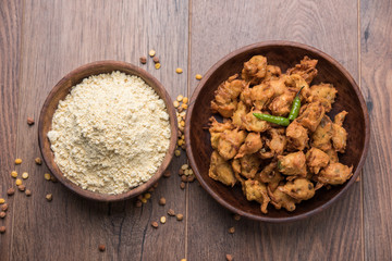 Chick pea flour or Besan powder in a ceramic or wooden bowl along with fried onion pakora or kanda bajji