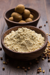 Chick pea flour or Besan powder in a ceramic or wooden bowl along with sweet Laddu or laddoo