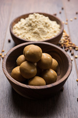 Chick pea flour or Besan powder in a ceramic or wooden bowl along with sweet Laddu or laddoo