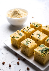 Chick pea flour or Besan powder in a ceramic or wooden bowl along with Gujrati Dhokla snack