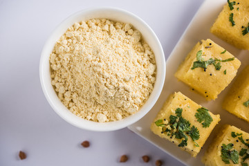 Chick pea flour or Besan powder in a ceramic or wooden bowl along with Gujrati Dhokla snack