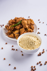 Chick pea flour or Besan powder in a ceramic or wooden bowl along with fried onion pakora or kanda bajji