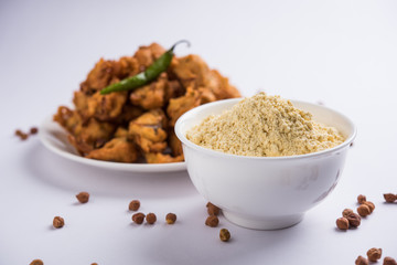 Chick pea flour or Besan powder in a ceramic or wooden bowl along with fried onion pakora or kanda bajji