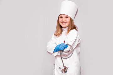 Smiling little girl in medical uniform and blue gloves looking at camera isolated on white