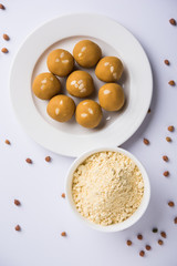 Chick pea flour or Besan powder in a ceramic or wooden bowl along with sweet Laddu or laddoo