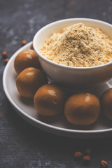 Chick pea flour or Besan powder in a ceramic or wooden bowl along with sweet Laddu or laddoo