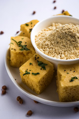Chick pea flour or Besan powder in a ceramic or wooden bowl along with Gujrati Dhokla snack