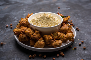 Chick pea flour or Besan powder in a ceramic or wooden bowl along with fried onion pakora or kanda bajji