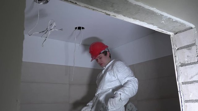 man making hole in ceiling plasterboard for electric installation.