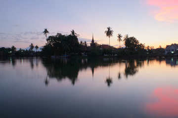 un temple bouddhiste qui refl&egrave;te sur un &eacute;tang lors d&rsquo;un magnifique couch&eacute; de soleil 