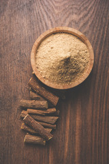 Ayurvedic Mulethi or Liquorice root stick or jeshthamadh powder served in a bowl over moody background