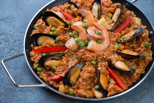Serving pan with seafood paella over blue stone background, studio shot, closeup