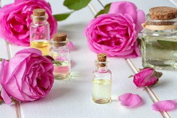 A bottle of rose essential oil with fresh roses