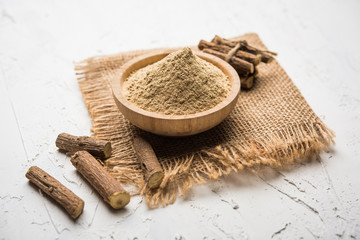 Ayurvedic Mulethi or Liquorice root stick or jeshthamadh powder served in a bowl over moody background