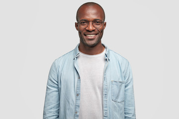 Horizontal shot of happy dark skinned male with positive smile on face, being in high spirit as...