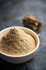 Ayurvedic Mulethi or Liquorice root stick or jeshthamadh powder served in a bowl over moody background